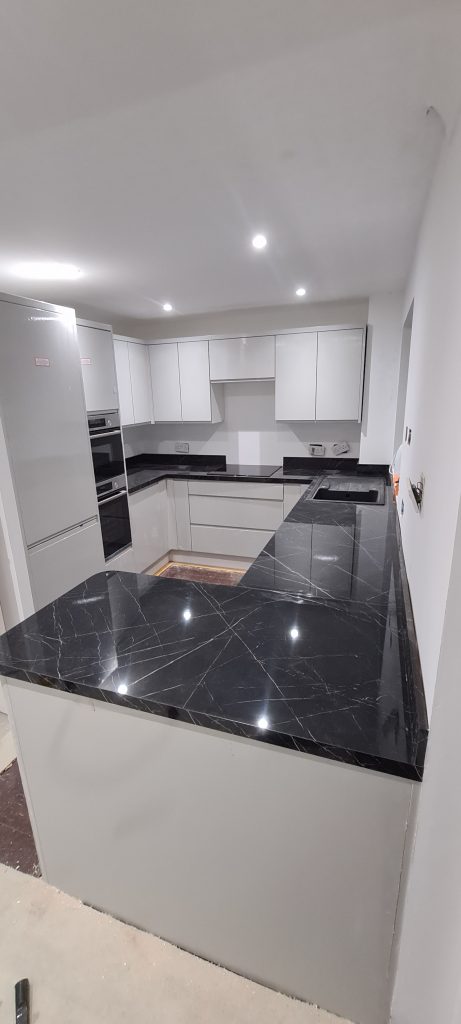 Modern kitchen with white cabinets and black marble countertops